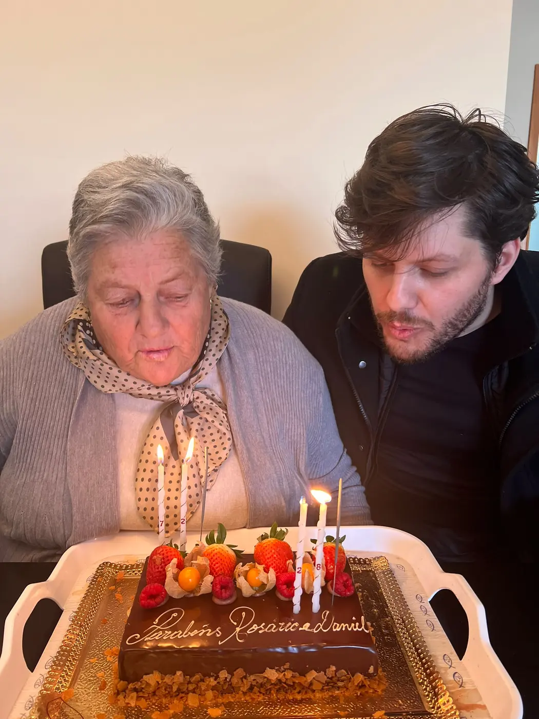 Fábio Daniel e a mãe inclinados sobre um bolo de aniversário
